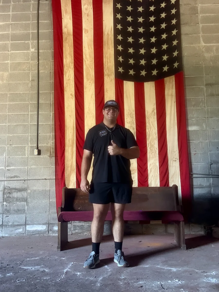 Devin Harvey, owner of Baldwin Removal Services, standing in front of an American flag